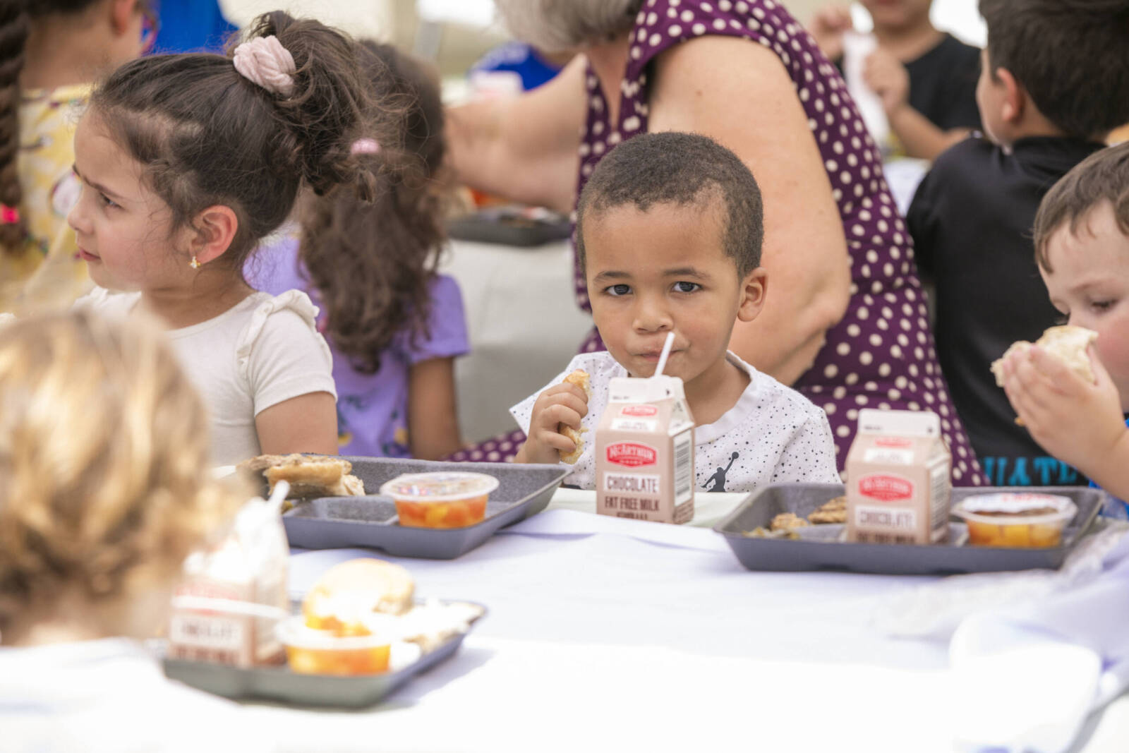 Boy eating food with other kids in cafeteria