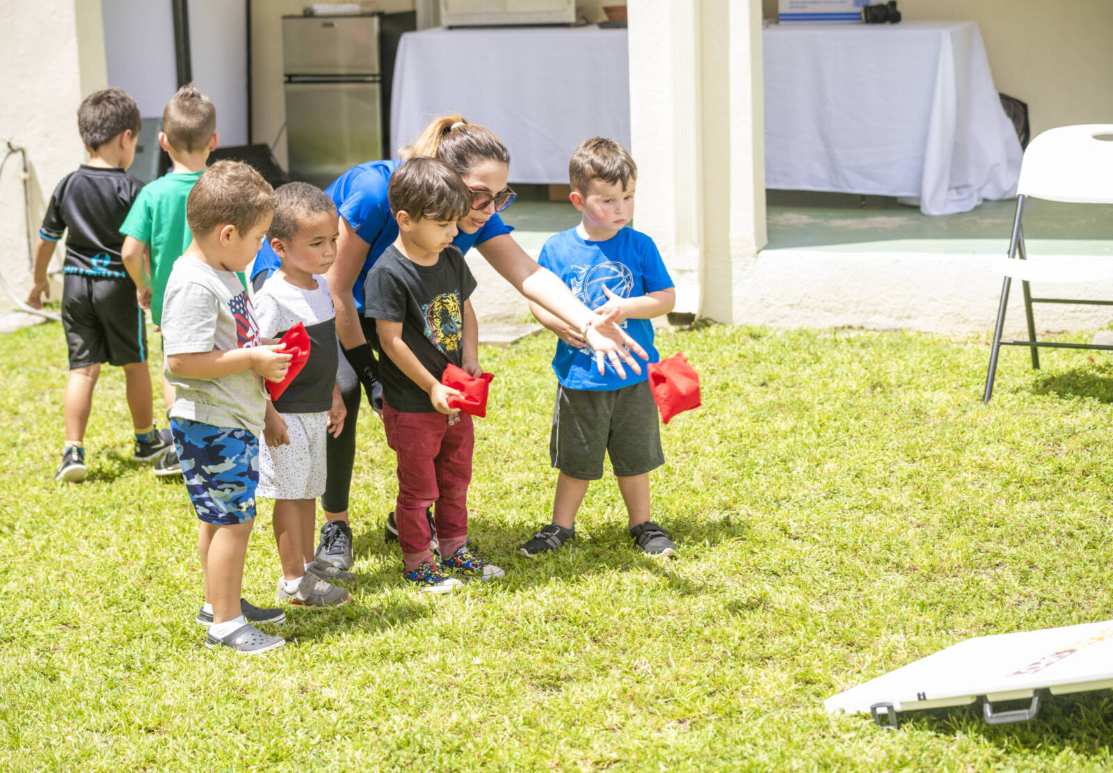 Woman and kids playing cornhole outslide