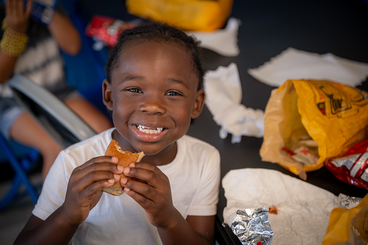 Young boy smiling while he eats lunch